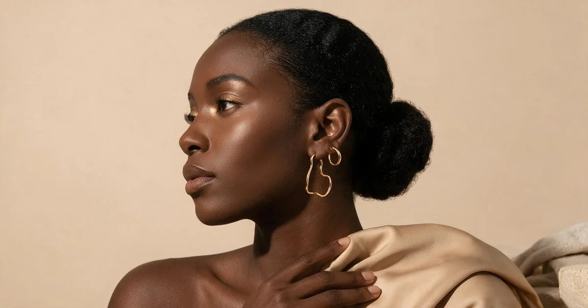 Ear stack on a model: a gold-tone irregular wave hoop in the first piercing with a plain sleeper above