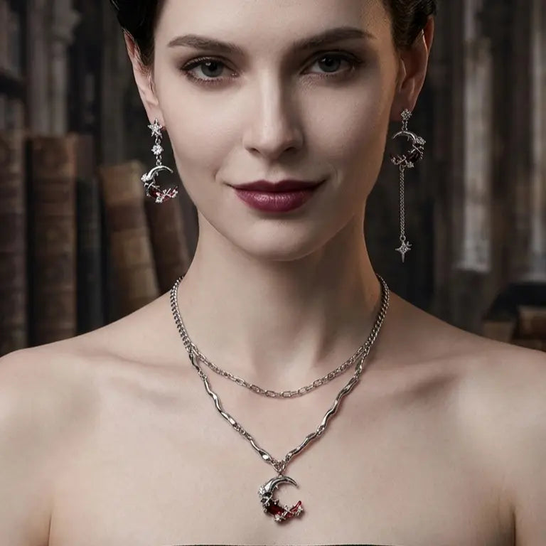 Woman with light skin tone and short dark brown hair wearing asymmetric silver-tone moon and star drop earrings — short crescent moon left earring and long crescent moon with chain and spike star drop right earring — paired with matching double-layer silver chain necklace with crescent moon red zircon pendant, deep burgundy lips, bare shoulder, dark gothic library background, AI-generated model image — earrings shown as part of coordinated set

