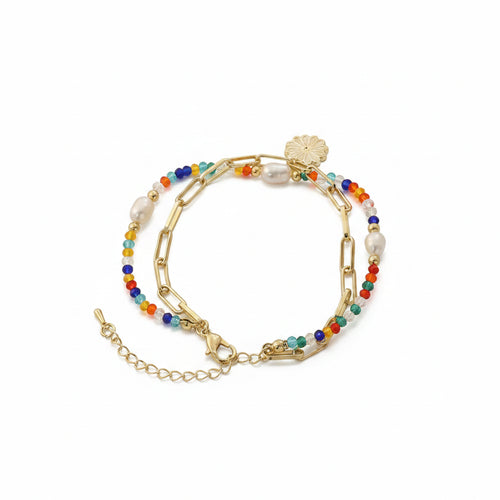 Double bracelet set coiled together on white background: multicolor seed bead and freshwater pearl strand with gold alloy paperclip chain and white daisy enamel charm pendant, both lobster clasps and extender chains visible, soft drop shadow

