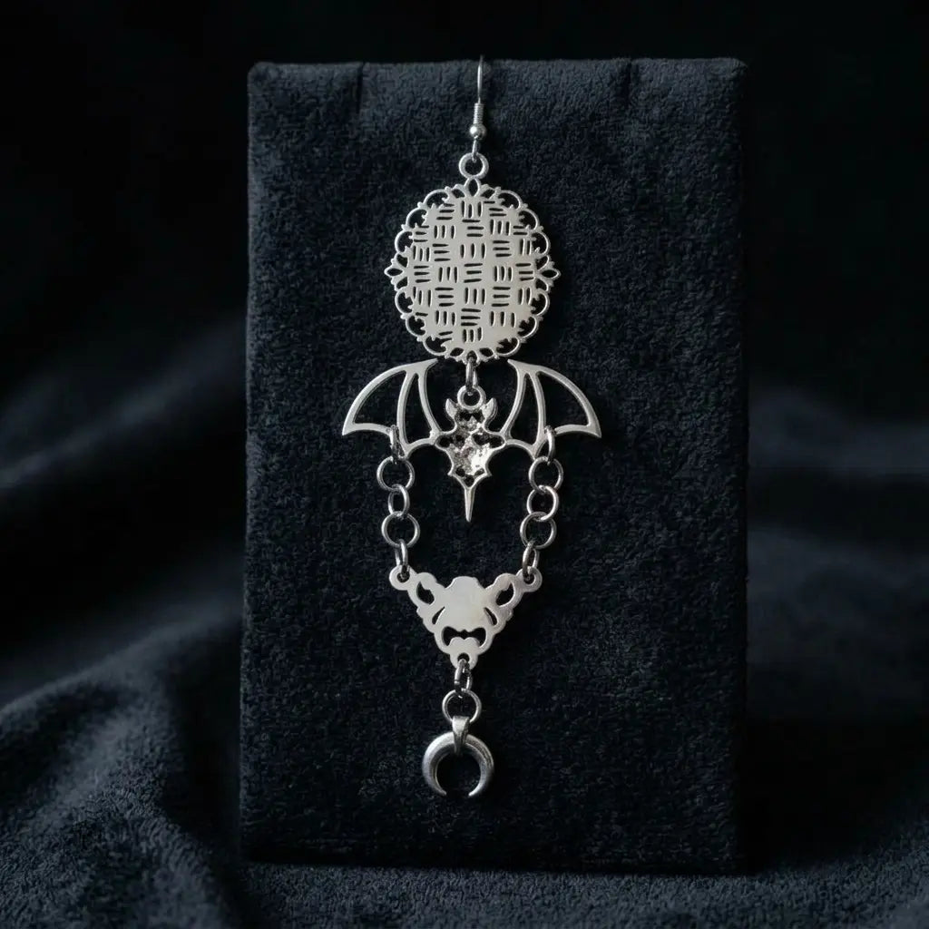 Single silver-tone gothic bat and moon drop earring on black velvet display stand — round filigree lattice top pendant, spread-wing bat with white crystal, bat skull face connector and crescent moon drop — please verify this image matches the correct product

