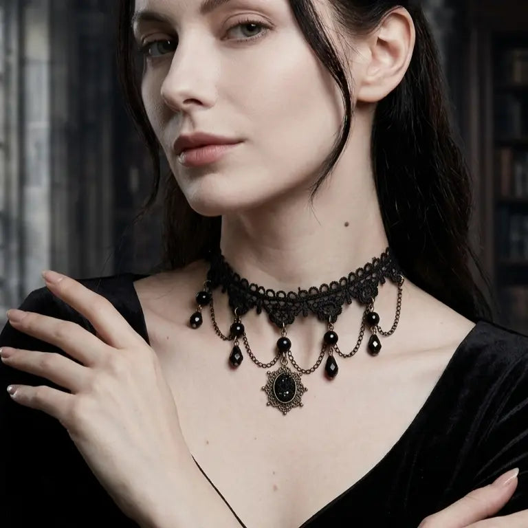 Woman with light skin tone and straight black hair wearing gothic black lace choker necklace with draped antique bronze chains, black teardrop crystal bead drops and sunburst black gemstone pendant, hands crossed on chest, black V-neck velvet top, dark gothic library background, AI-generated model image

