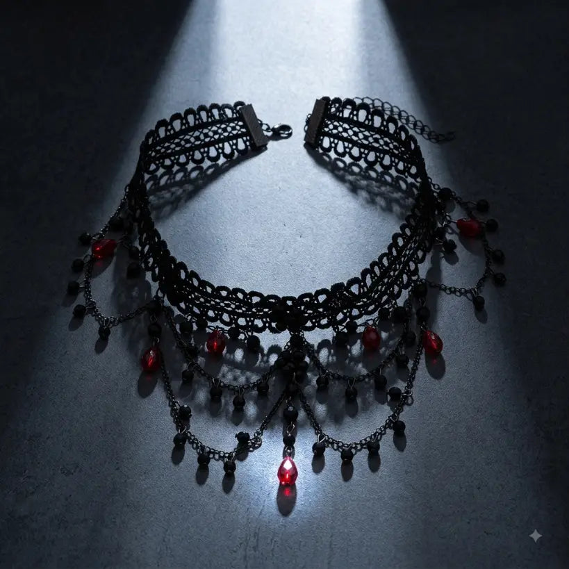 Gothic black lace choker necklace with multi-tier gunmetal chain fringe, black faceted crystal bead drops and deep red teardrop crystal accents, displayed flat on dark grey concrete surface under dramatic single overhead spotlight creating circular halo effect with glowing red center crystal drop, black background, AI-generated image

