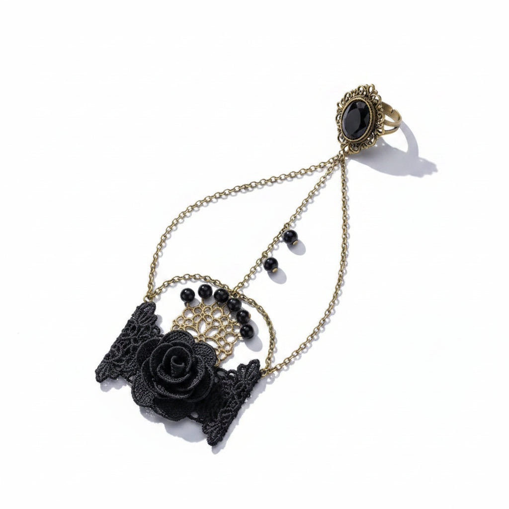 Gothic black lace square wrist cuff slave bracelet ring set with 3D black fabric rose centerpiece on antique bronze diamond mesh filigree base, black round bead drops, two antique bronze chains with black bead accents connecting to adjustable antique bronze filigree oval black onyx ring; isolated on white background with soft drop shadow

