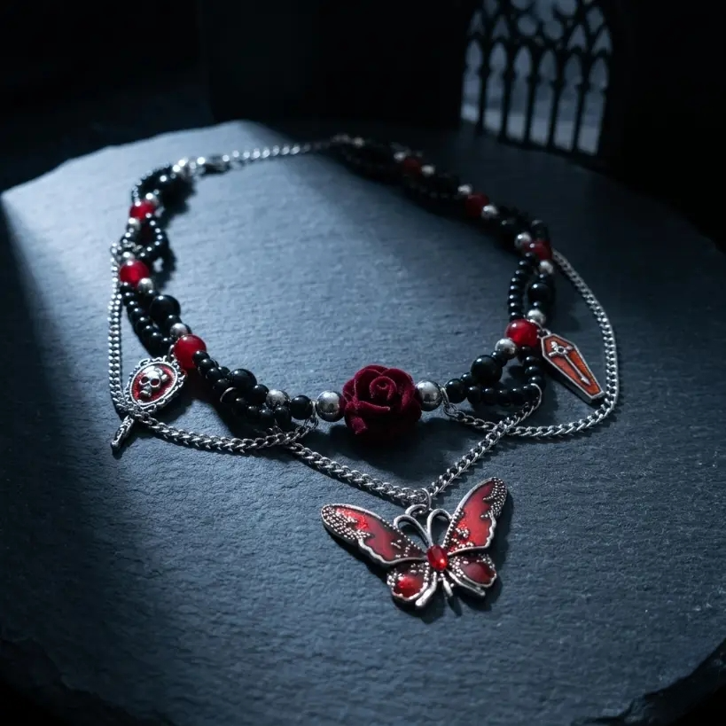 Gothic black and red bead choker necklace with skull cameo dagger charm, deep red 3D rose, red coffin cross charm and red enamel butterfly pendant, displayed on dark blue-grey textured stone slab with gothic arched window prop, dramatic single spotlight, black background, AI-generated image

