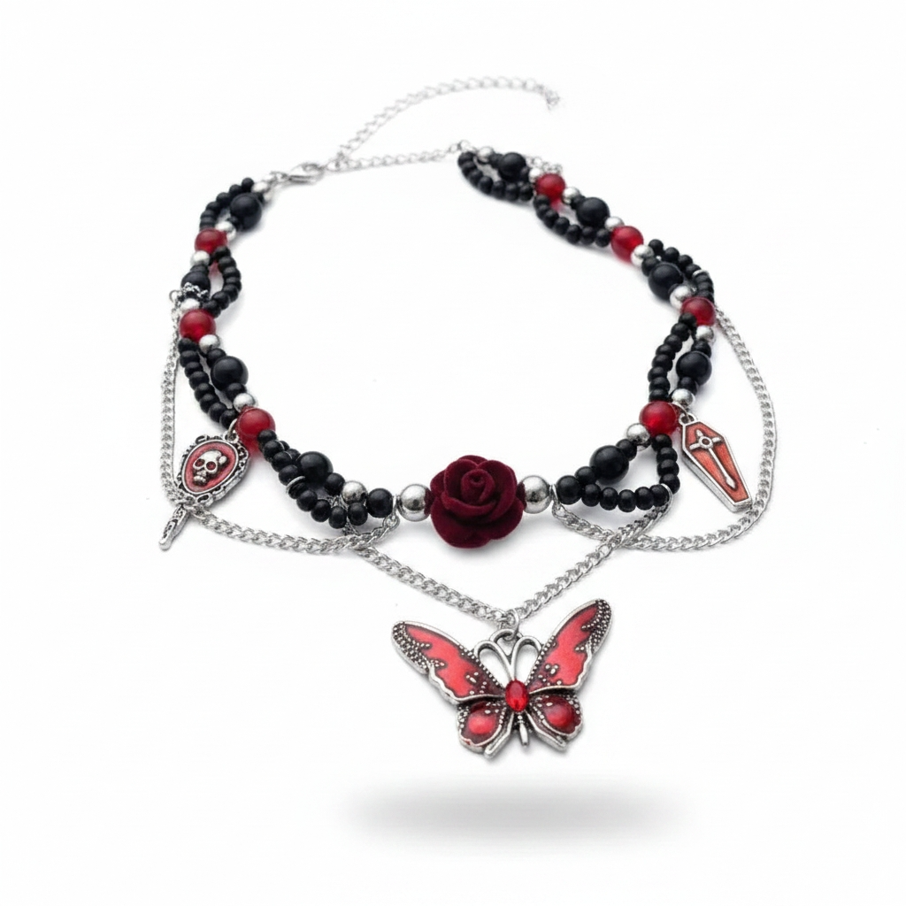 Gothic choker necklace on white background: double-strand black and red round bead chain with draped silver chains; skull cameo charm with dagger, deep red 3D rose centerpiece, red coffin cross charm, and large red enamel butterfly pendant with silver filigree wings and red crystal body; lobster clasp and silver extender chain visible, soft drop shadow

