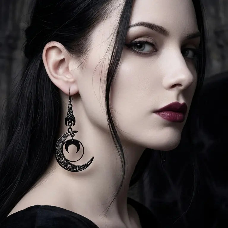 Woman with light skin tone and straight long black hair wearing gothic gunmetal black filigree crescent moon drop earring on right ear — black fish hook, flame claw connector, large hollow scrollwork crescent moon with nested small solid crescent inside — deep burgundy lips, smoky eye makeup, black top, dark gothic stone wall with lancet arch texture background, AI-generated model image

