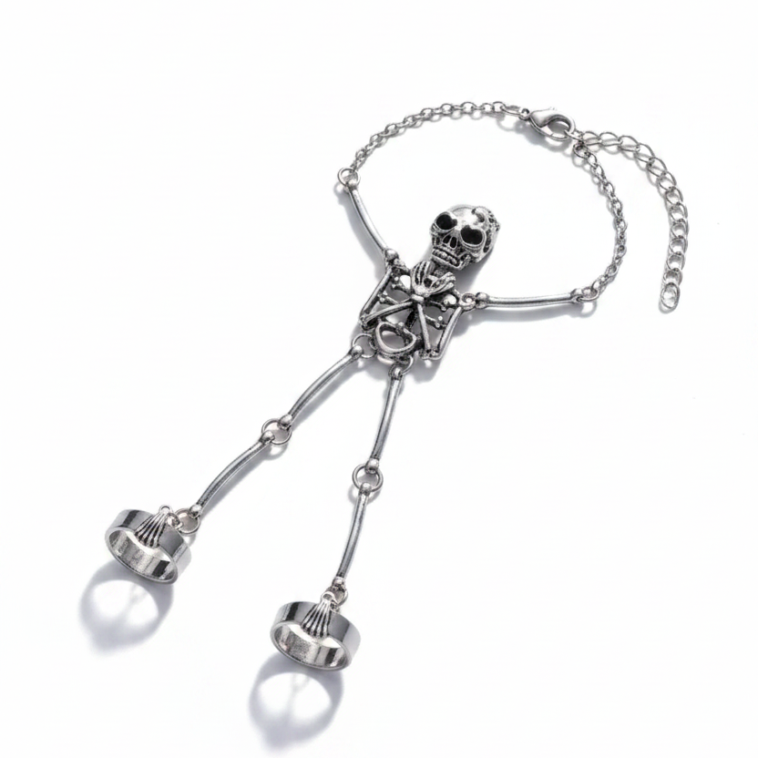 Gothic silver-tone alloy full-body skeleton hand chain bracelet double ring set — skull head with black crystal eyes connected to adjustable silver cable chain wrist bracelet, tubular bone arms and legs extending to two silver scallop-edge band finger rings; isolated on white background with soft drop shadow
