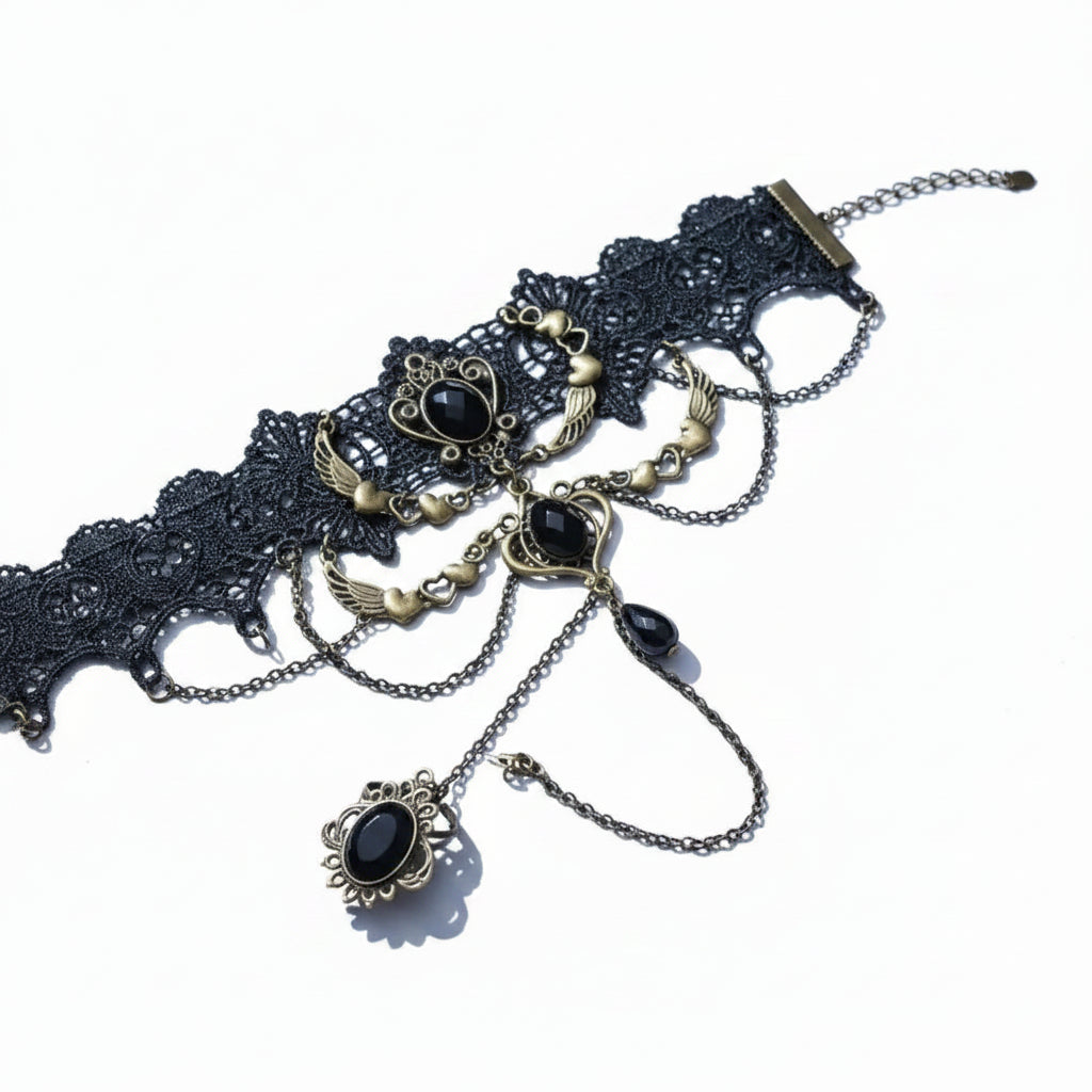 Gothic black lace wide cuff slave bracelet ring set with antique bronze angel wing and black faceted onyx oval gemstone on bracelet, three draped antique bronze chains with heart and wing charms, black teardrop gemstone drop, connected to adjustable antique bronze filigree oval black onyx ring; magnetic clasp; isolated on white background with soft drop shadow


