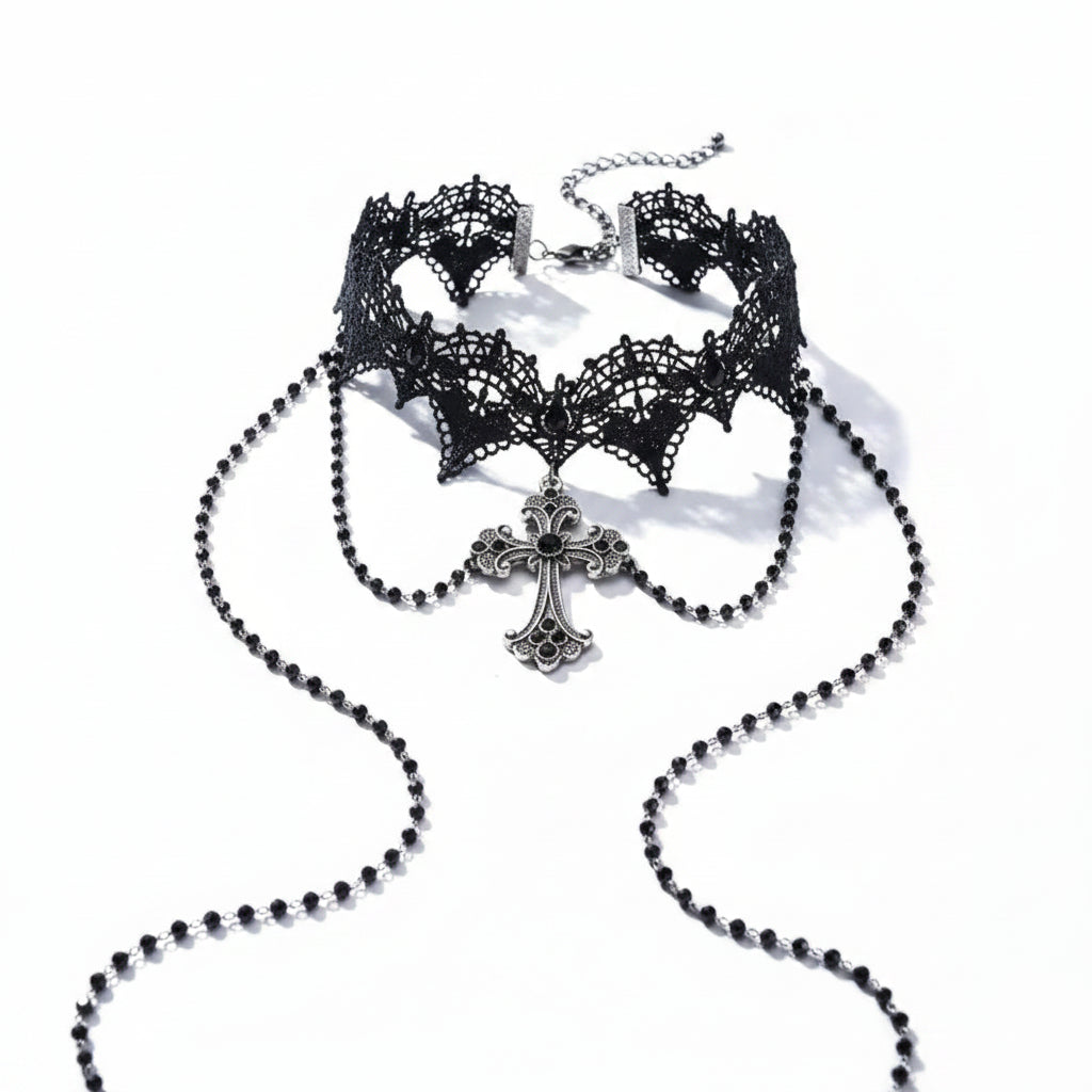 Gothic black lace bat-wing scalloped wide choker necklace with silver filigree cross pendant set with black crystal, two long black bead rosary chains draped from sides, lobster clasp and silver extender chain visible, isolated on white background with directional shadow