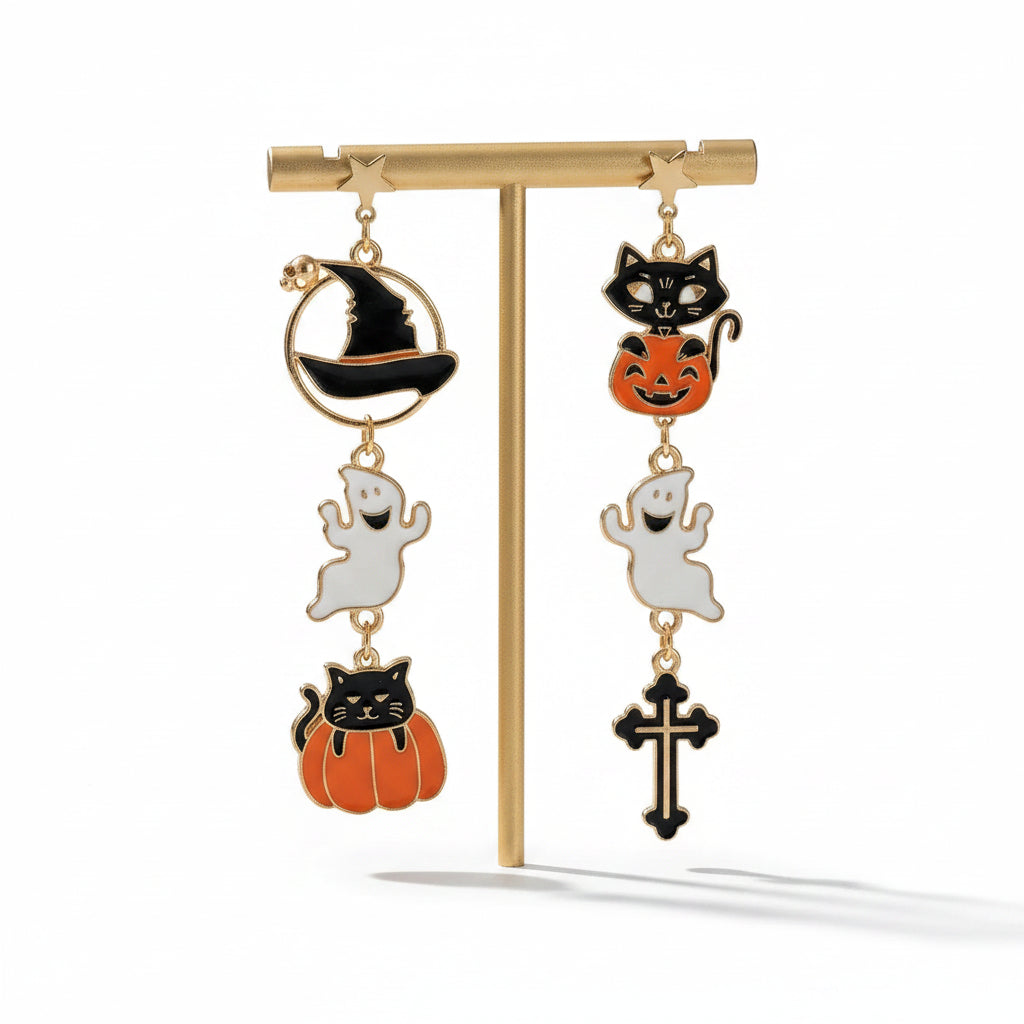 Halloween asymmetric drop stud earring set displayed on gold T-bar stand: left earring with gold star stud, gold ring frame with black enamel witch hat and orange brim, white enamel smiling ghost drop, black cat in orange pumpkin drop; right earring with gold star stud, black cat sitting on orange jack-o-lantern pumpkin drop, white enamel ghost drop, black enamel gothic cross drop; isolated on white background

