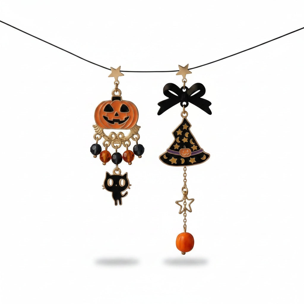 Halloween asymmetric drop stud earring set suspended on wire: left earring with gold star stud, orange enamel jack-o-lantern pumpkin pendant on gold scrollwork base, black and amber faceted crystal bead drops and cute black cat charm; right earring with gold star stud, black bow, black enamel witch hat pendant with gold star moon pattern and orange pumpkin badge, gold open star connector and orange round bead drop; white background

