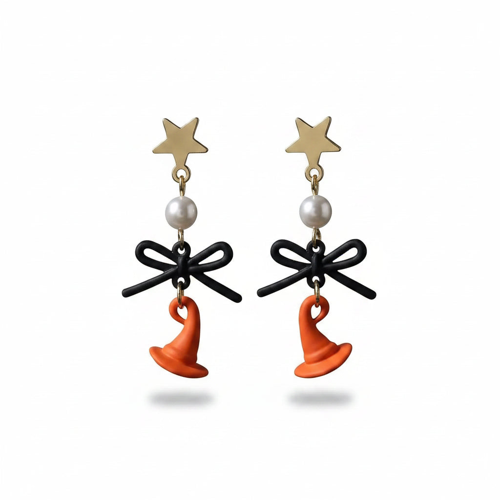 Pair of Halloween gold-tone star stud drop earrings with white faux pearl bead, matte black bow and orange enamel witch hat pendant; isolated on white background with soft drop shadow

