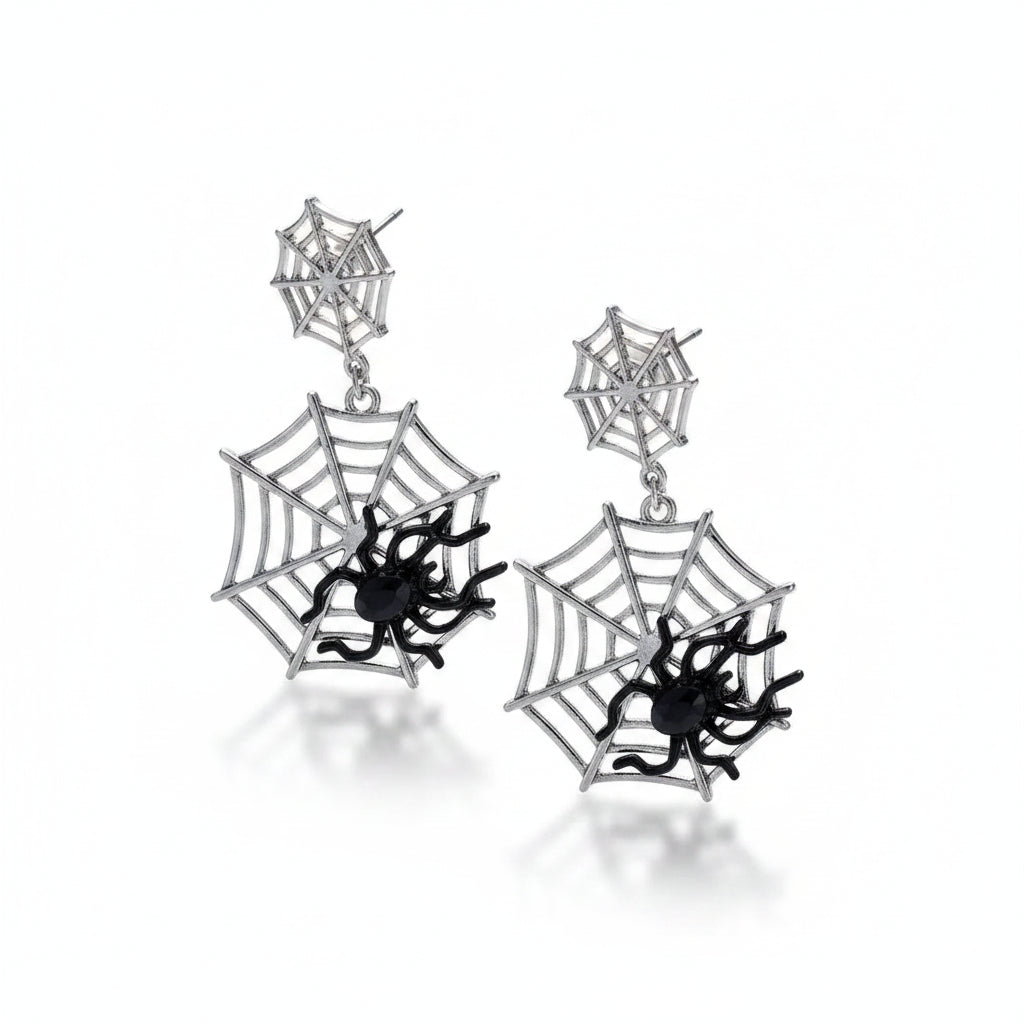 Pair of gothic silver-tone alloy double spider web drop stud earrings: small spider web stud top connected by short chain to large spider web pendant with black enamel 3D spider at center; isolated on white background with soft drop shadow

