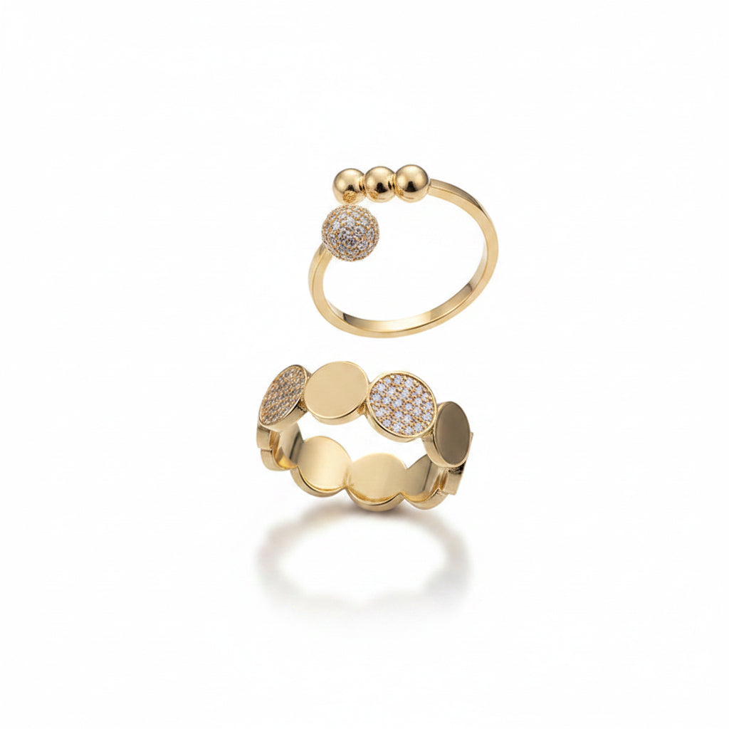 Two gold alloy adjustable rings displayed on white background: top is an open band ring with micro-pave zirconia ball and three gold bead ends; bottom is a wide band ring with alternating micro-pave zirconia and smooth gold oval discs

